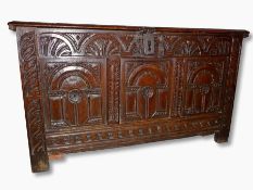 A late 17th/early 18th century oak coffer, three panelled front having lunette carved frieze over