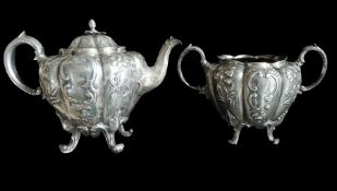 A silver melon-shaped teapot, embossed floral decoration, flame finial to cover, scroll supports and