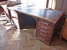 A 20th century oak kneehole desk with inset leather writing top, an arrangement of nine drawers (one