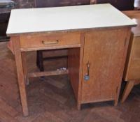 A formica top kitchen table with frieze drawer and side cupboard on square legs and towel rail to