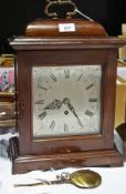 A mahogany bracket timepiece with ornate brass ring handle to the top, having silvered dial, on