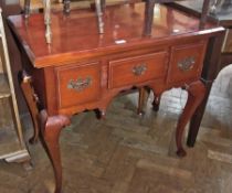 A reproduction mahogany lowboy with three drawers, with brass swan-neck handles, on cabriole