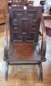 A 19th century oak chair having panelled back and seat, open arms and on 'X' supports 

   Live