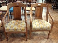 A pair of Biedermeyer walnut open arm tub chairs, each with curved back, central splat, curved arms,