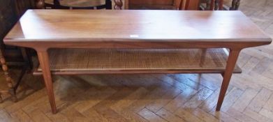 A mid 20th century rectangular coffee table, with cane shelf below, on tapering supports, 135cm wide