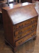 A reproduction figured walnut bureau with hinged fall front enclosing arrangement of pigeonholes and