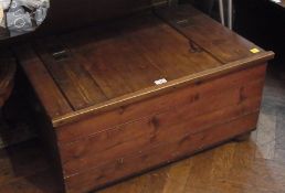 An old pine blanket box, of plank construction with hinged lid on bun feet, width 84cms