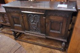 A late 19th century oak sideboard having central cupid carved panel flanked with two panel doors, on