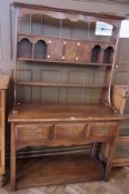 A modern oak dresser with pigeonholes and cupboards to top, with drawers below with brass swan-