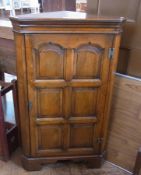 A 20th century oak corner cupboard, panelled door, on bracket feet, 69cm wide