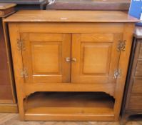 A 20th century light oak cupboard, panelled doors with brass shaped hinges and circular handles,