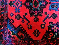 A Persian style wool rug, red ground with blue border and central medallions