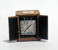 A French travel alarm clock with carrying handle raised on ball feet, within a handmade oak case