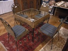 Garden table with four matching chairs, the table glass topped with wicker surround, on metal