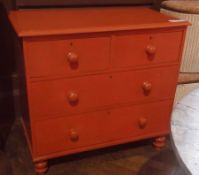 A red painted pine chest of two short and two long drawers, on turned supports, 90cm wide approx.