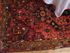 Iranian wool rug, red ground with central lozenge with blue, orange and brown pattern, 230cm x 120cm