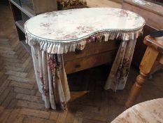 A 20th century kidney-shaped dressing table with floral top and curtains revealing two long drawers,