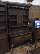 A reproduction oak dresser, with open plate rack and central cupboard with two frieze drawers below,