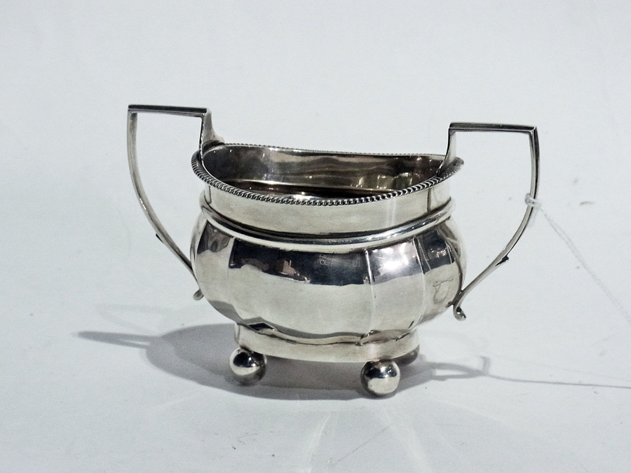 Silver sugar bowl, gadrooned rim, oval form, on four ball feet having angular hoop handles,