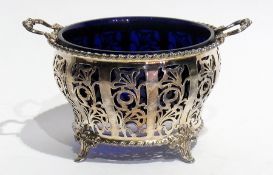 A silver sugar bowl, with floral fretwork decoration, twin handles, blue glass liner, raised on