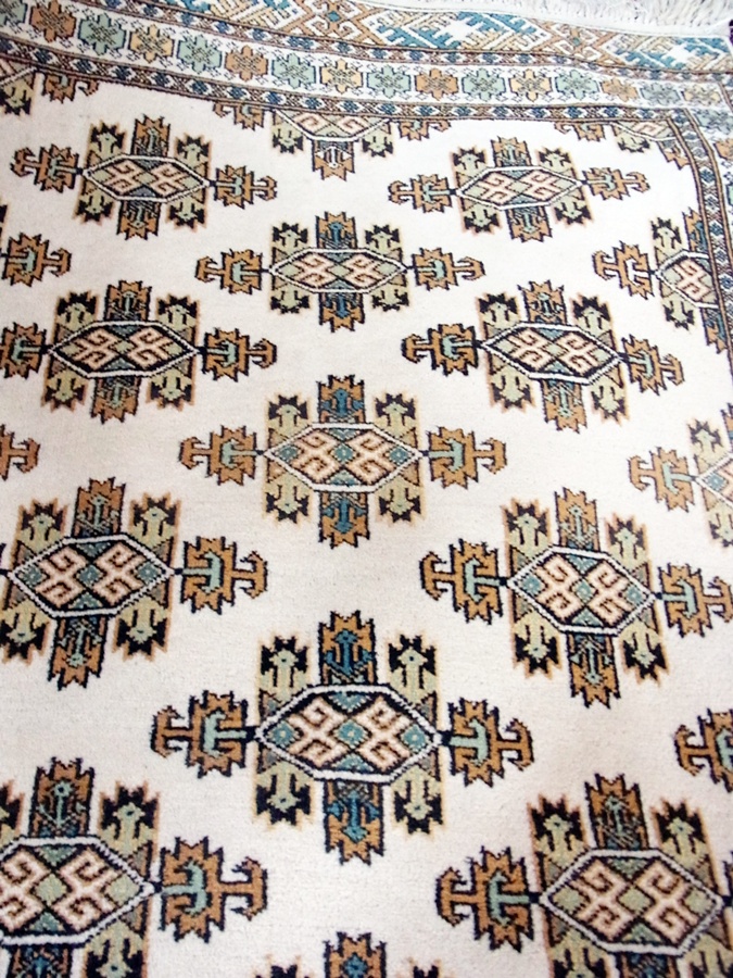 Persian wool rug of cream ground, with green and orange medallions and geometric borders