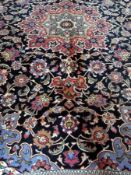Persian wool rug with central flowerhead medallion, on midnight-blue field, with allover scrolling