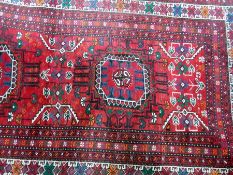 Eastern wool rug of Caucasian-style, with two elephant foot guls, on a red ground, geometric borders