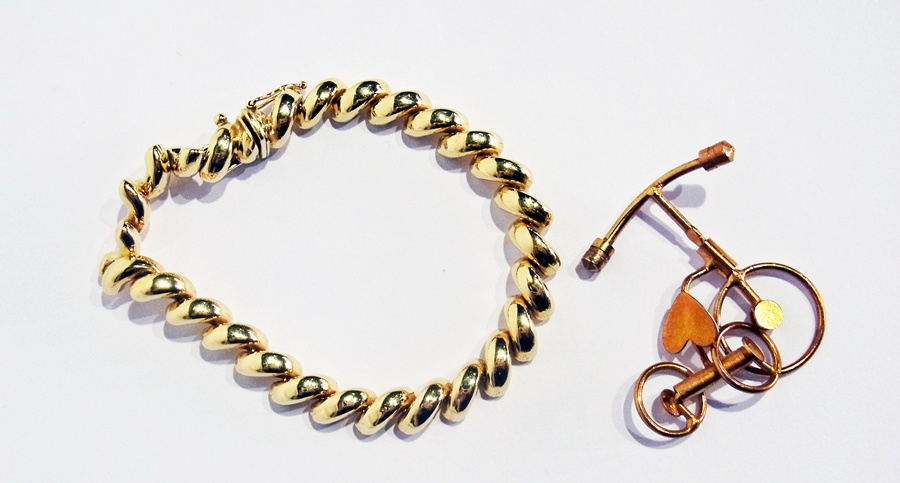 A 14K gold bracelet with a gilt metal novelty bicycle