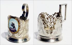 A Russian white metal and enamel tea glass holder together with another (2)