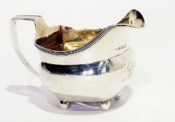 A Georgian silver cream jug with tapering handle and relief reeded border, on bun feet, London 1806,