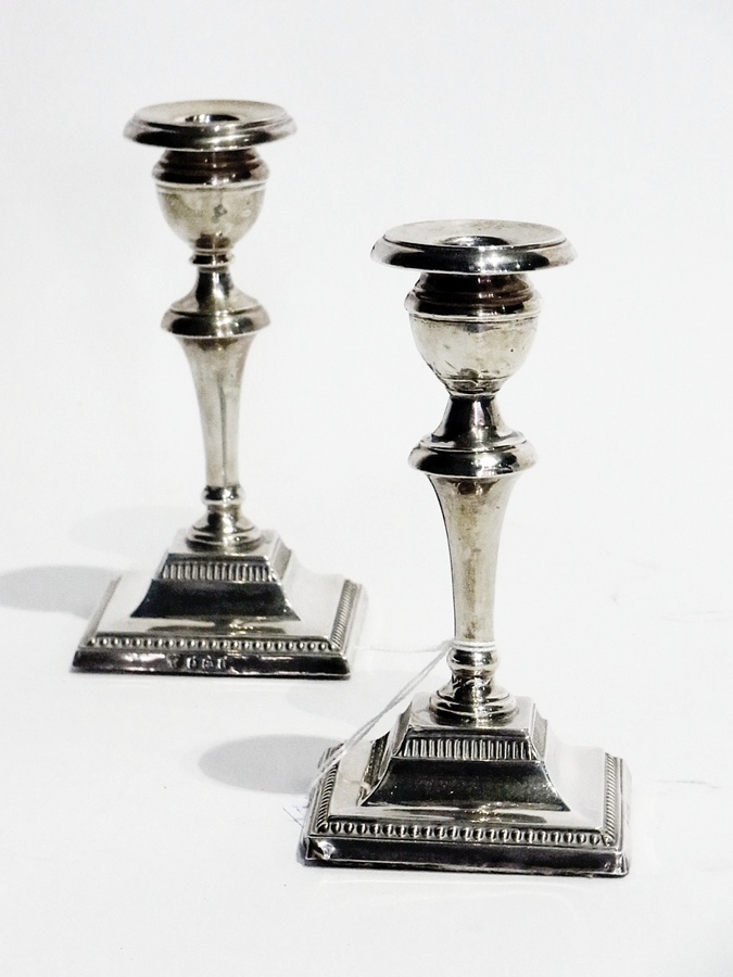 A pair of early 20th century silver short candlesticks, with baluster-shaped to tapering body, on