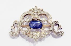 A sapphire and diamond brooch set elongated oval central sapphire stone, within diamond set scroll