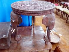 An Indian carved hardwood circular occasional table, on elephant mask supports, 46cm diameter
