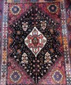 Persian wool rug, central ivory and red medallion, on black ground with red borders