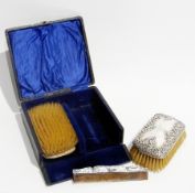 A Victorian silver backed pair of gentleman's hairbrushes with foliate C-scroll pattern and comb, in