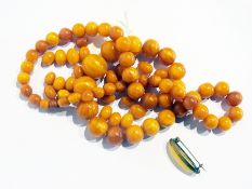 String of butterscotch or egg-yolk polished amber circular beads, 73g approx., sundry loose beads