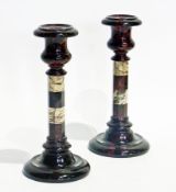 A pair of polished stone candlesticks with circular red stone sconces above octagonal white and