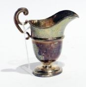 An Edwardian silver helmet-shaped cream jug, with foliate scroll handle, reeded body to raised
