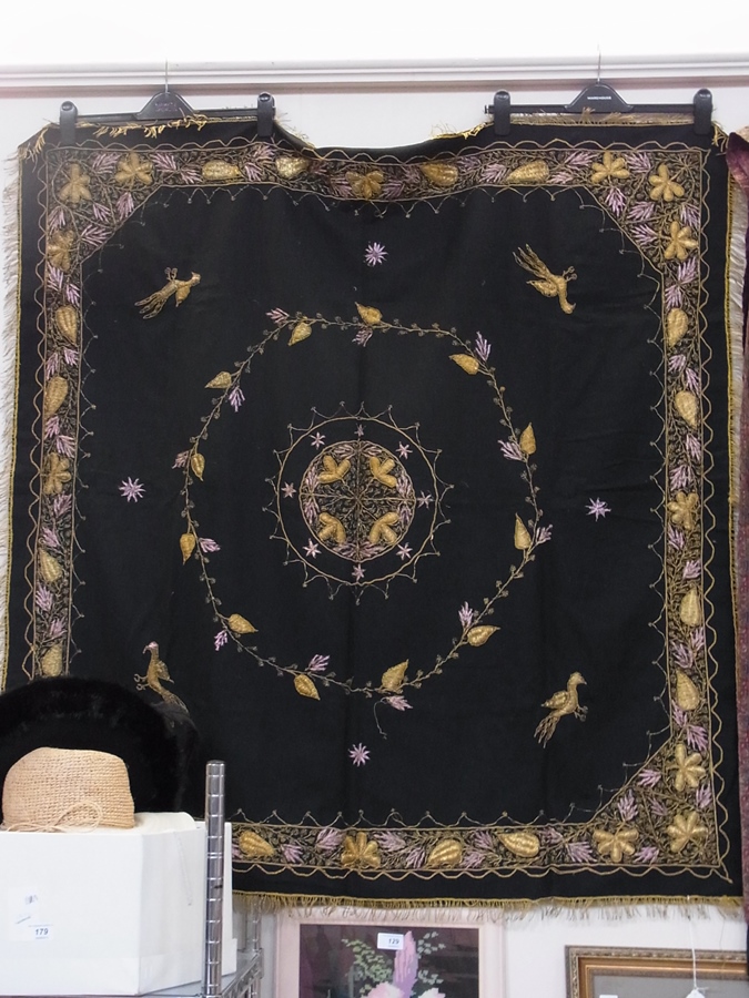 A large black tapestry panel, with gold thread embroidery, fringing, decorated with birds and