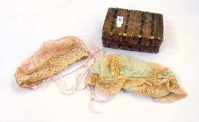 Two lace and satin mob caps with ribbons, one green, one pink in small wicker box