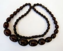 A red amber-type bead necklace of oval graduated beads