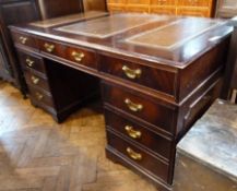 A reproduction mahogany pedestal desk, with inset writing surface, three frieze drawers with three