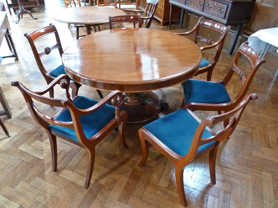 A Victorian-style mahogany circular-topped dining table with moulded edge and plain frieze, raised