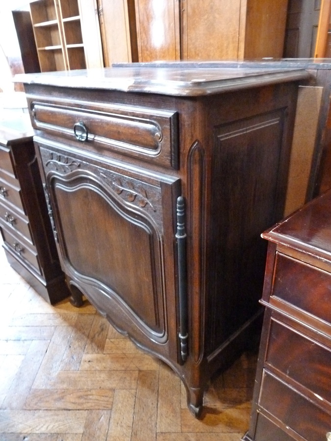A French oak side cupboard, with wavy edge moulded top, frieze drawer, with panelled cupboard below,