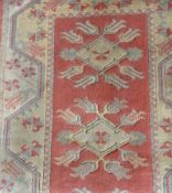 Wool rug in Persian style design, the brick red ground with three foliate lozenge medallions,