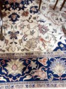 Large "Indo-Persian" wool carpet, the cream ground with central brick red and blue floral medallion,