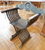 A stained oak X-frame chair with carved back, solid seat with open slat supports, on a platform