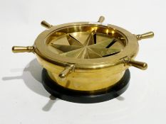 A brass mortar and pestle, a brass ashtray in the form of ship's wheel, a circular clear glass plate