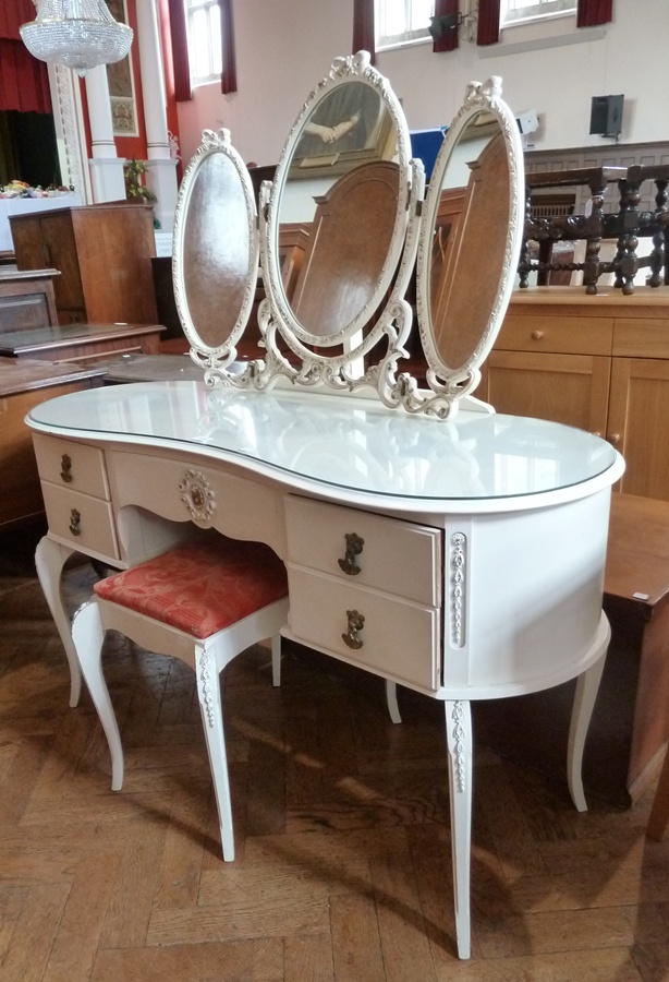 A reproduction white painted kidney-shaped dressing table, with triple mirror back, central frieze