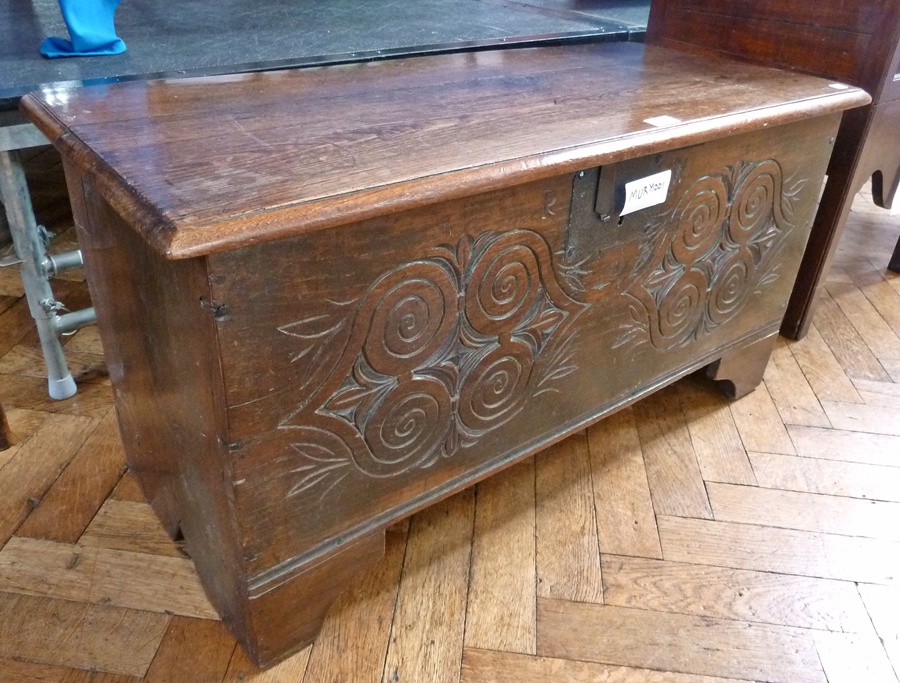 An 18th century carved oak plank coffer, the top with moulded edge, the interior fitted with trinket